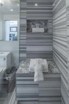 a bathroom with a bench with towels and a sink at Skyline Escape in the Heart of Downtown in San Diego