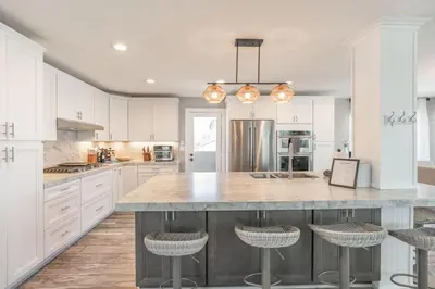 a kitchen with white cabinets and a large island with bar stools at Surfside Charmer One Block to Beach in San Diego
