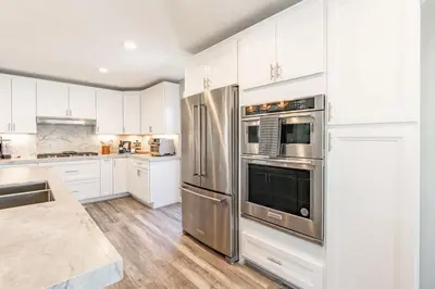 a kitchen with stainless steel appliances and white cabinets at Surfside Charmer One Block to Beach in San Diego