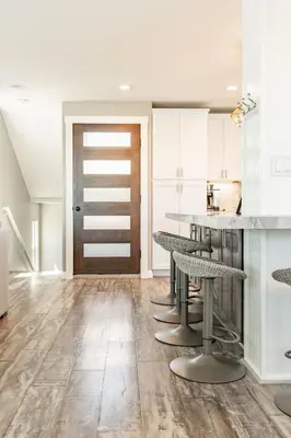 a kitchen with white cabinets and a counter with stools at Surfside Charmer One Block to Beach in San Diego