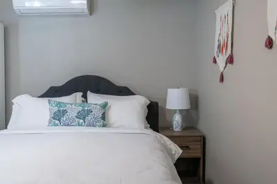 a bedroom with a white bed with pillows and a table at Surfside Studio Steps to Ocean in San Diego