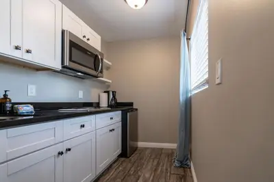 a kitchen with white cabinets and a microwave at Surfside Studio Steps to Ocean in San Diego