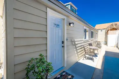 a house with a white door and a table and chairs at Surfside Studio Steps to Ocean in San Diego