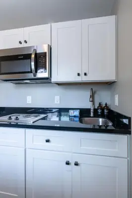a kitchen with white cabinets and a sink and a microwave at Cozy Beachside Studio in San Diego