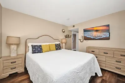 a bedroom with a white bed and wooden floors at Newport Paradise - Oceanfront Home by the Pier in Newport Beach