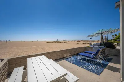 a bench and an umbrella next to the beach at Newport Paradise - Oceanfront Home by the Pier in Newport Beach