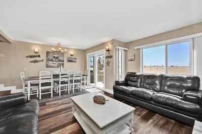 a living room with a leather couch and a table at Newport Paradise - Oceanfront Home by the Pier in Newport Beach