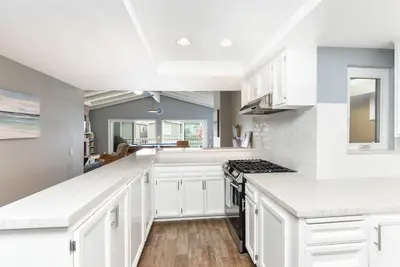 a white kitchen with white cabinets and a stove at 5 Bedroom Home with Pool Table steps to the Beach in Newport Beach