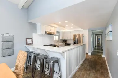 a kitchen with white cabinets and bar stools at 5 Bedroom Home with Pool Table steps to the Beach in Newport Beach