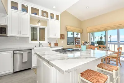 a kitchen with white cabinets and a large kitchen island at Multi Level Oceanfront Home with Patio on the Beach, Fire pit and 2 car garage in Newport Beach