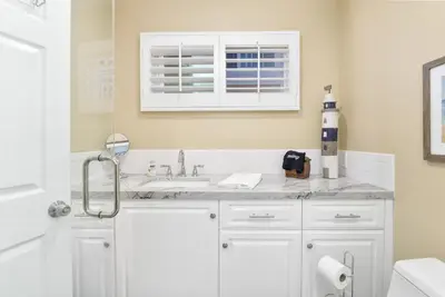 a white bathroom with a sink and a window at Multi Level Oceanfront Home with Patio on the Beach, Fire pit and 2 car garage in Newport Beach