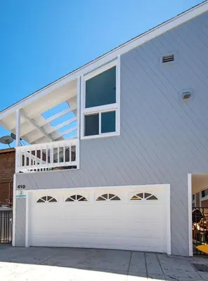 a house with a white garage door and windows at Multi Level Oceanfront Home with Patio on the Beach, Fire pit and 2 car garage in Newport Beach
