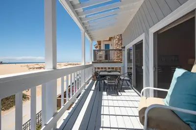 a screened porch with a table and chairs on the beach at Multi Level Oceanfront Home with Patio on the Beach, Fire pit and 2 car garage in Newport Beach
