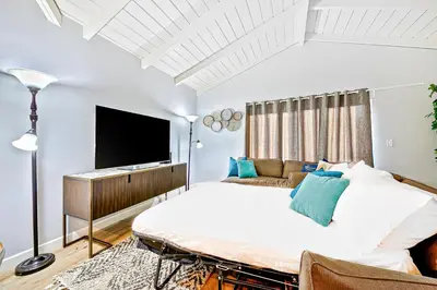 a bedroom with a large bed and a flat screen tv at Cozy 3 Bedroom Across from Playground on the Beach in Newport Beach
