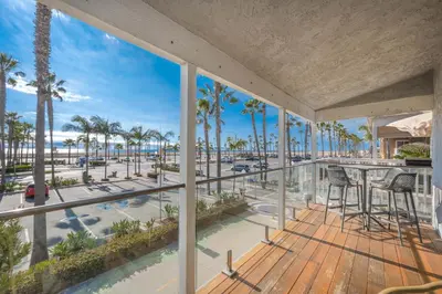 a balcony with a view of the beach and palm trees at 3 Bedroom home on the beach steps from Balboa Pier in Newport Beach