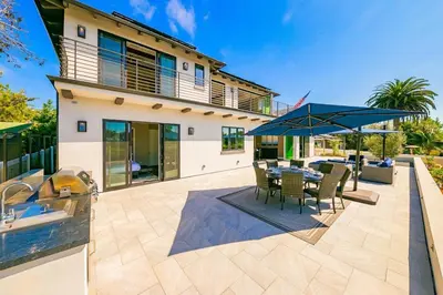 a patio with a table and chairs and an umbrella at Luxury Bird Rock Home with Private Pool, Hot Tub & Fire Pit! in San Diego