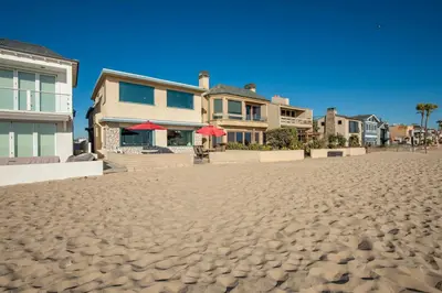 a house on a sandy beach next to houses at Upstairs 2 Bedroom Home with Ocean Views on 65th St in Newport Beach