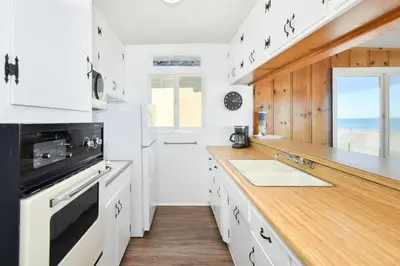 a kitchen with white cabinets and a wooden counter top at Upstairs 2 Bedroom Home with Ocean Views on 65th St in Newport Beach