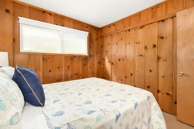a bedroom with a bed and a window and wooden walls at Upstairs 2 Bedroom Home with Ocean Views on 65th St in Newport Beach