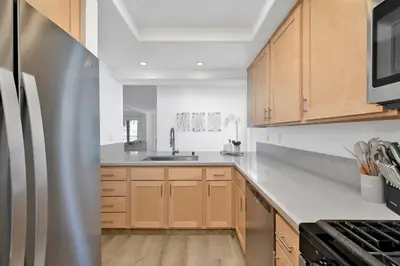 a kitchen with wooden cabinets and a stainless steel refrigerator at NEW - 3 Bedroom near the Balboa Pier and Fun Zone with AC in Newport Beach