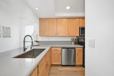 a kitchen with wooden cabinets and a stainless steel sink at NEW - 3 Bedroom near the Balboa Pier and Fun Zone with AC in Newport Beach