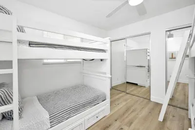 a bedroom with white bunk beds and a mirror at NEW - 3 Bedroom near the Balboa Pier and Fun Zone with AC in Newport Beach