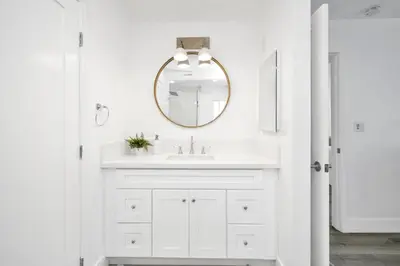 a white bathroom with a sink and a mirror at 6 Bedroom Duplex near the Balboa Pier and Fun Zone with AC in Newport Beach