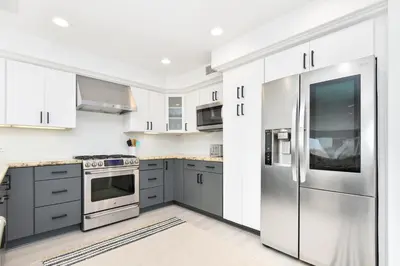 a kitchen with white cabinets and a stainless steel refrigerator at Luxury 3 Bedroom walk to Beach & Pier in Newport Beach