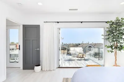 a bedroom with white walls and a large sliding glass door at Luxury 3 Bedroom walk to Beach & Pier in Newport Beach