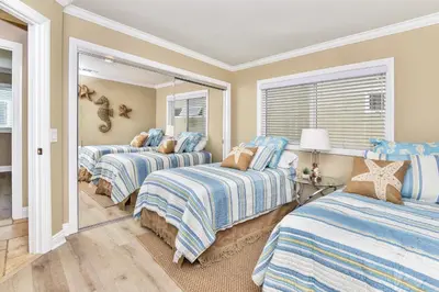 a room with three beds and a mirror at 1 House from the Sand with Rooftop Deck on 28th Street in Newport Beach