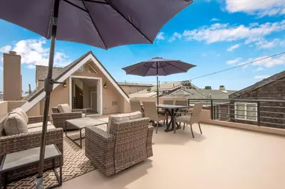 a balcony with a table and chairs and an umbrella at 1 House from the Sand with Rooftop Deck on 28th Street in Newport Beach