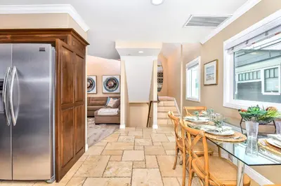 a kitchen and dining room with a table and a refrigerator at 1 House from the Sand with Rooftop Deck on 28th Street in Newport Beach