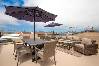a patio with a table and chairs and an umbrella at 1 House from the Sand with Rooftop Deck on 28th Street in Newport Beach