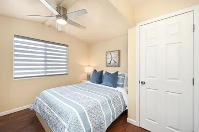 a bedroom with a bed with blue pillows and a ceiling fan at 6 Bedroom home located 2 houses in from the Beach in Newport Beach