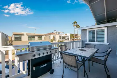 a grill on a balcony with a table and chairs at 6 Bedroom home located 2 houses in from the Beach in Newport Beach