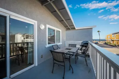a patio with a table and chairs on a balcony at 6 Bedroom home located 2 houses in from the Beach in Newport Beach