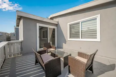a patio with chairs and a table on a balcony at 6 Bedroom home located 2 houses in from the Beach in Newport Beach