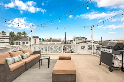 a patio with a couch and a grill on a roof at 7 Bedroom Duplex Home with Rooftop & Peek-A-Boo Ocean View in Newport Beach