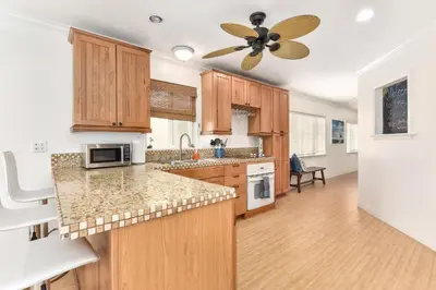 a kitchen with wooden cabinets and a ceiling fan at 7 Bedroom Duplex Home with Rooftop & Peek-A-Boo Ocean View in Newport Beach