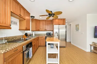 a kitchen with wooden cabinets and a ceiling fan at 7 Bedroom Duplex Home with Rooftop & Peek-A-Boo Ocean View in Newport Beach