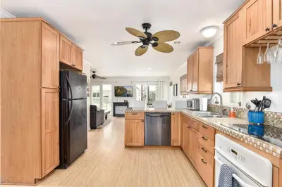 a kitchen with wooden cabinets and a black refrigerator at 4 Bedroom Home with Rooftop & Peek-A-Boo Ocean View in Newport Beach