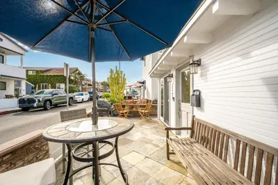 a patio with a table and a blue umbrella at Freshly Renovated Beach House Steps to the Beach in Newport Beach