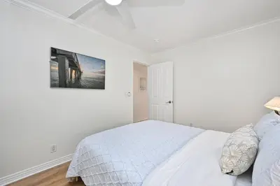 a white bedroom with a bed and a painting on the wall at Freshly Renovated Beach House Steps to the Beach in Newport Beach