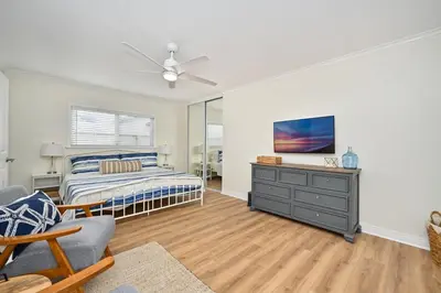 a bedroom with a bed and a dresser with a tv at Freshly Renovated Beach House Steps to the Beach in Newport Beach