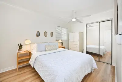 a white bedroom with a large bed and a mirror at Freshly Renovated Beach House Steps to the Beach in Newport Beach