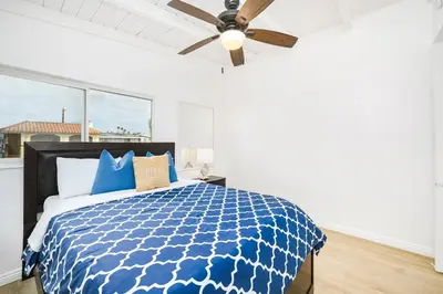 a bedroom with a blue bed with a ceiling fan at 2 Bedroom Upstairs with Balcony Steps from the Sand in Newport Beach
