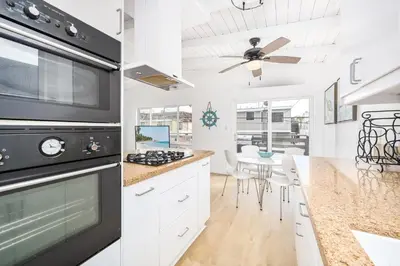 a kitchen with white cabinets and a black stove top oven at 2 Bedroom Upstairs with Balcony Steps from the Sand in Newport Beach