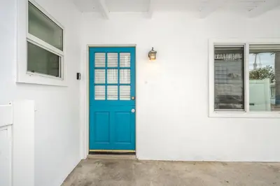 a blue door on a white house at 2 Bedroom Upstairs with Balcony Steps from the Sand in Newport Beach
