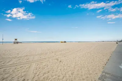 a view of a sandy beach with a pier at 2 Bedroom Upstairs with Balcony Steps from the Sand in Newport Beach