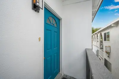 a blue door on the side of a white building at 2 Bedroom Upstairs with Balcony Steps from the Sand in Newport Beach
